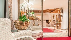 A cozy living room with patterned sofas, a red carpet, and a decorative plant centerpiece. - Austria Bellevue (Soelden)