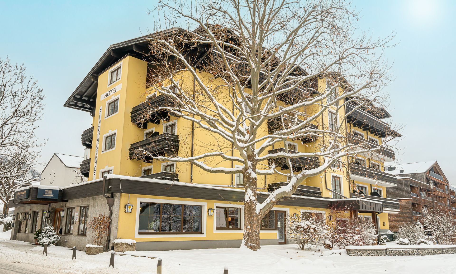 Ein mehrstöckiges Hotel mit gelber Fassade, Balkonen und verschneiter Landschaft.