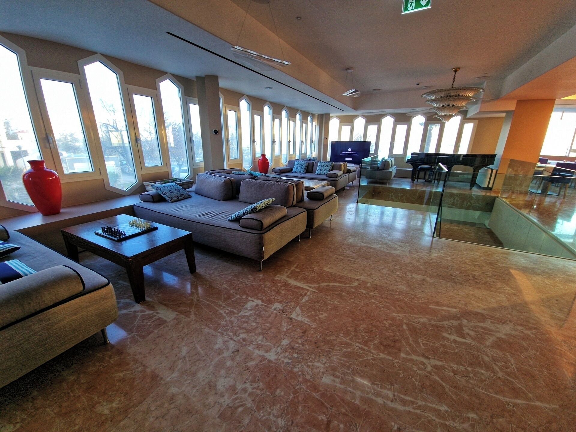 Een ruime lobby met een grote bank, een bijzettafeltje en een rode vaas.