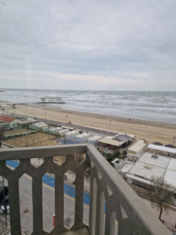 A beach view from a balcony with a lifeguard tower, beach huts, and a parking area. - City Hotel (Senigallia)