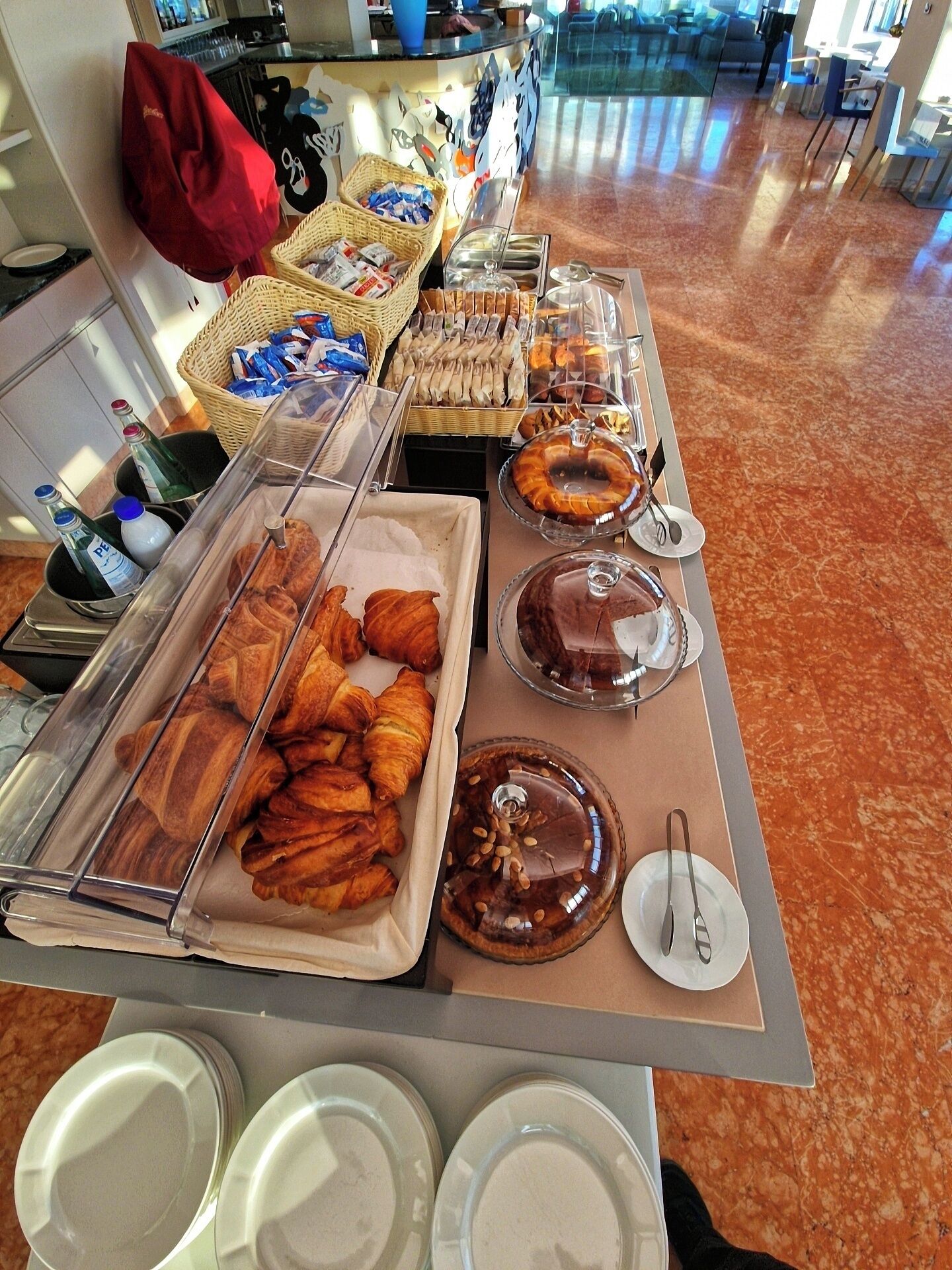Ein reichhaltiges Buffet mit verschiedenen Speisen, darunter Gebäck und Desserts, sowie eine Theke mit Flaschen und Körben.