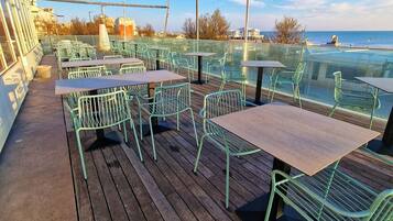 Una terraza con mesas y sillas, con vista a un cuerpo de agua.