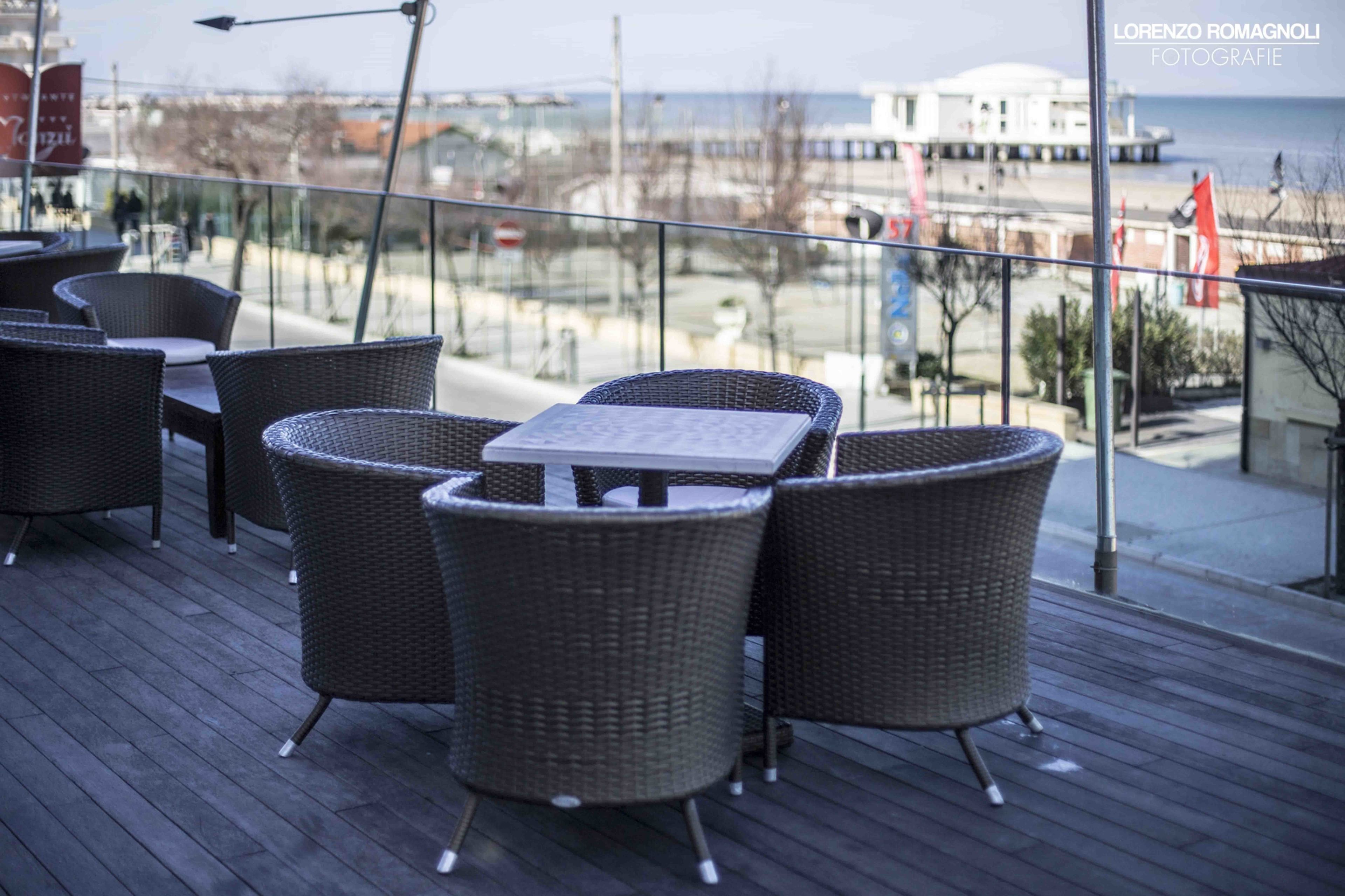 Een terras met rieten meubels en uitzicht op zee.
