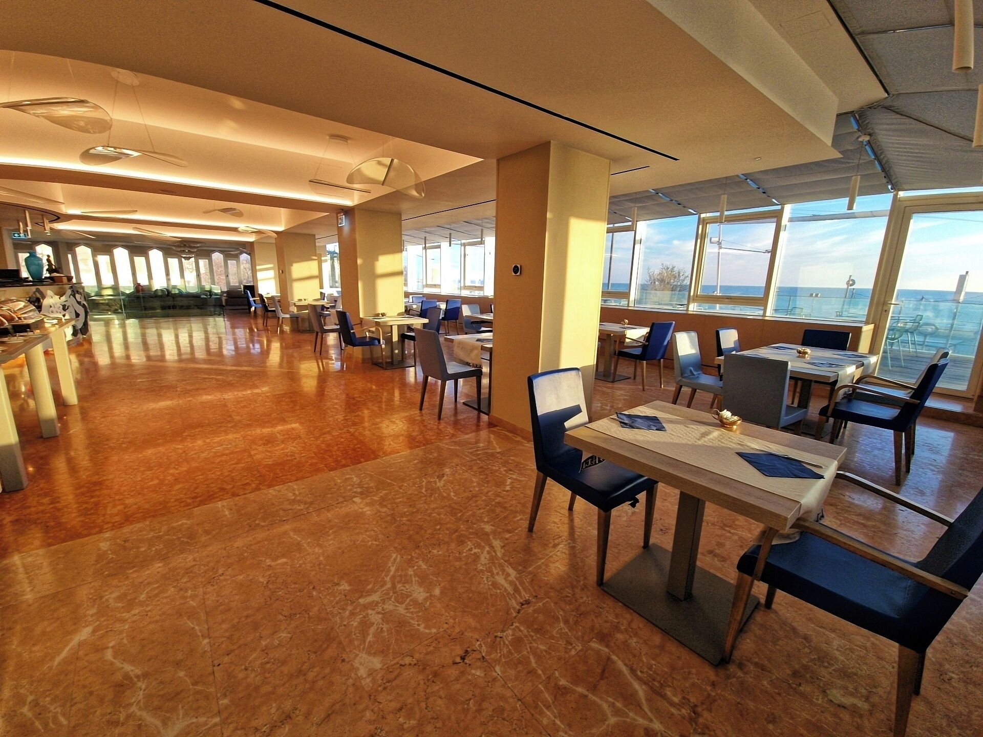 Un comedor amplio con techos altos, ventanas grandes y vista al mar.