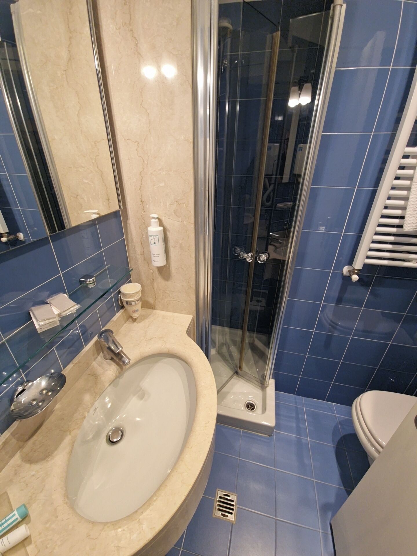 Un baño con ducha envuelta en vidrio, lavamanos con espejo y retrete.