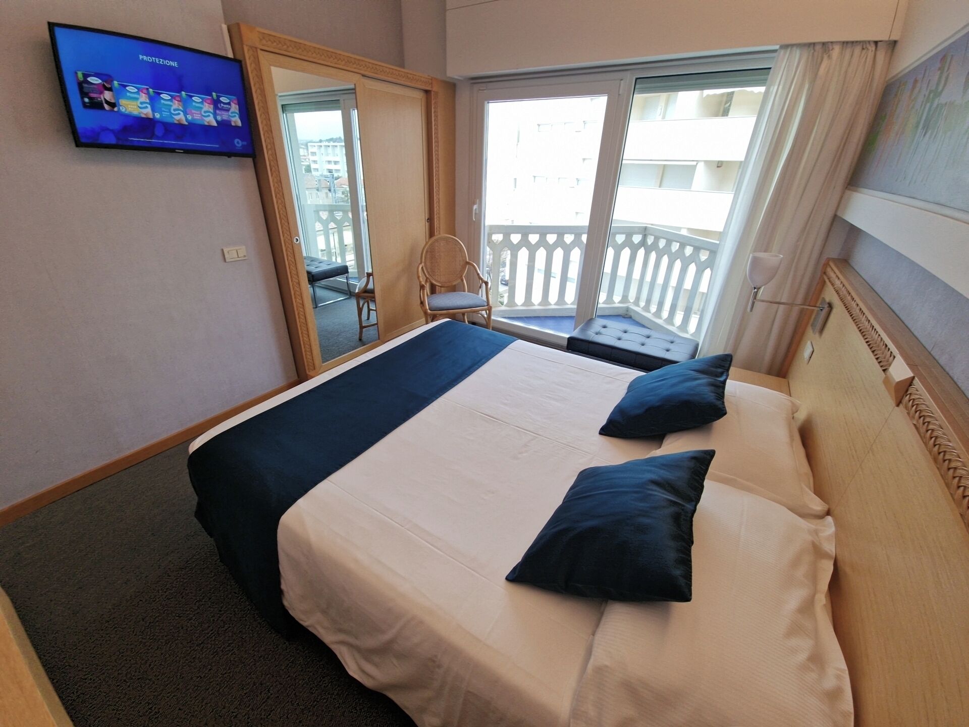 Ein Hotelzimmer mit Bett, Fernseher, Balkon mit Blick und Stuhl.