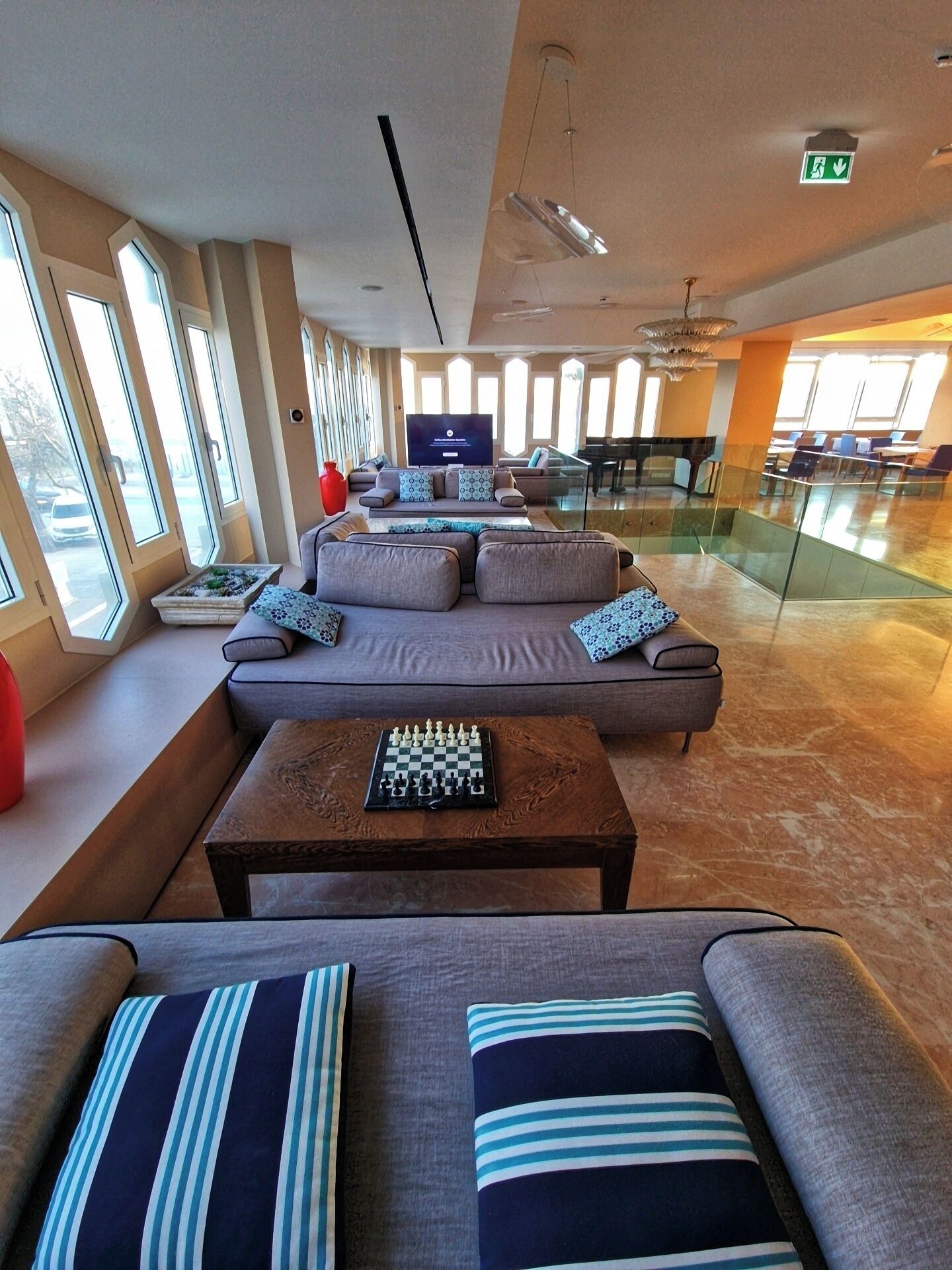 A spacious lounge area with a large sofa set, a chess table, and a television screen.