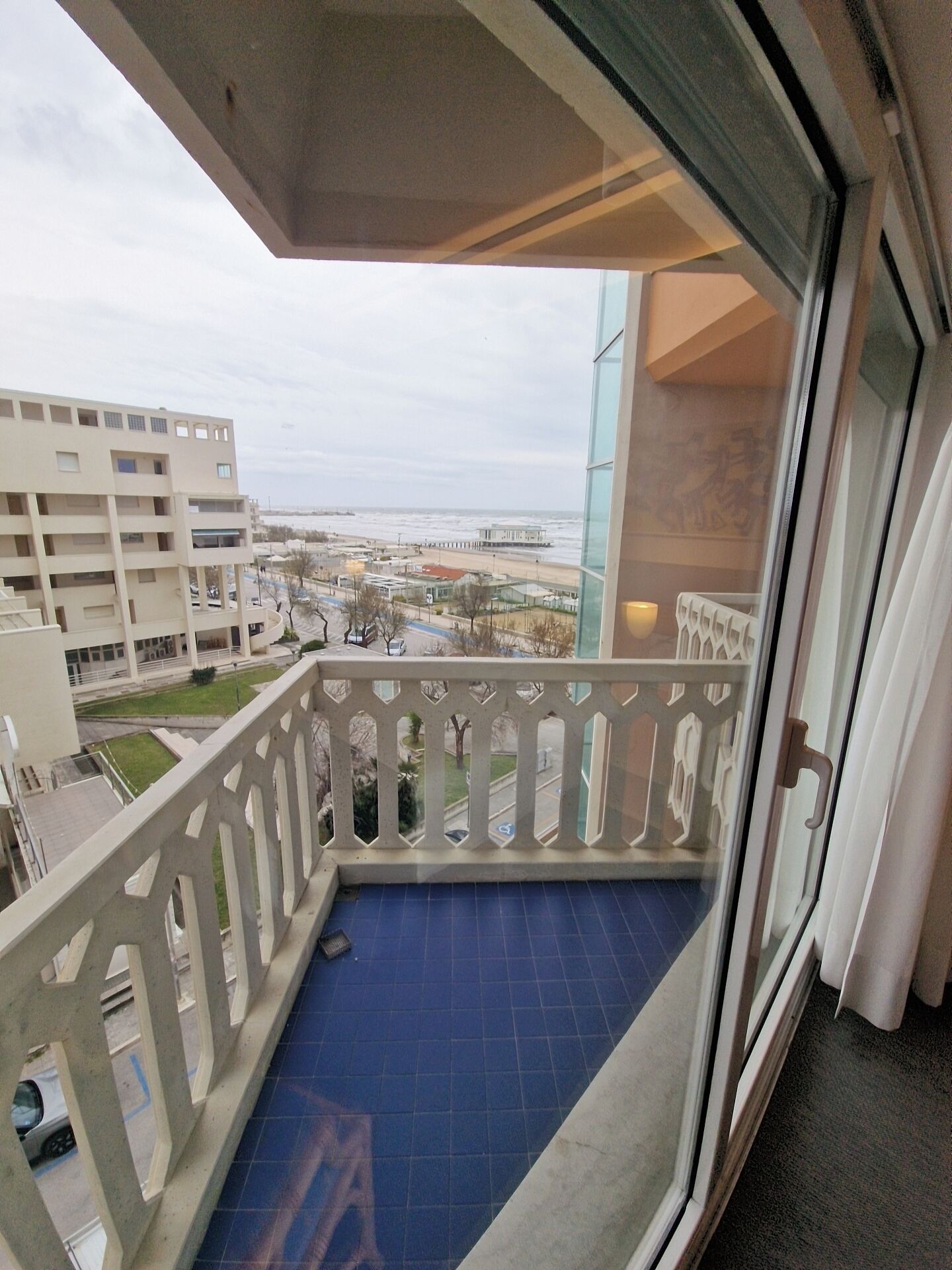 Un balcon donnant sur une plage et des immeubles.