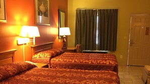 Une chambre d’hôtel avec deux lits, un ventilateur de plafond et une fenêtre avec des rideaux.