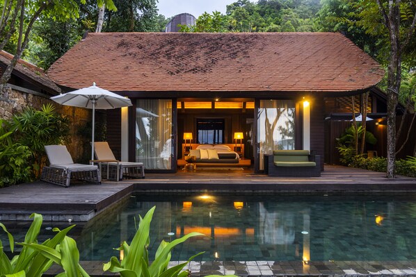 Una villa moderna con piscina, un dormitorio con cama y zona de estar, y un patio con sillones de descanso.