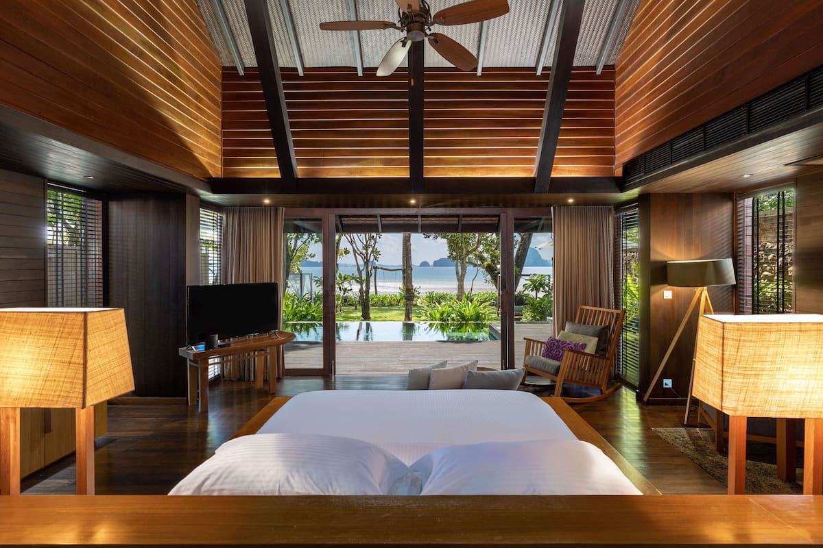 A spacious bedroom with a large bed, a television, and a view of the ocean.