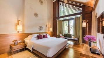A spacious bedroom with a large bed, wooden headboard, and a view of the outdoors through a window with curtains.
