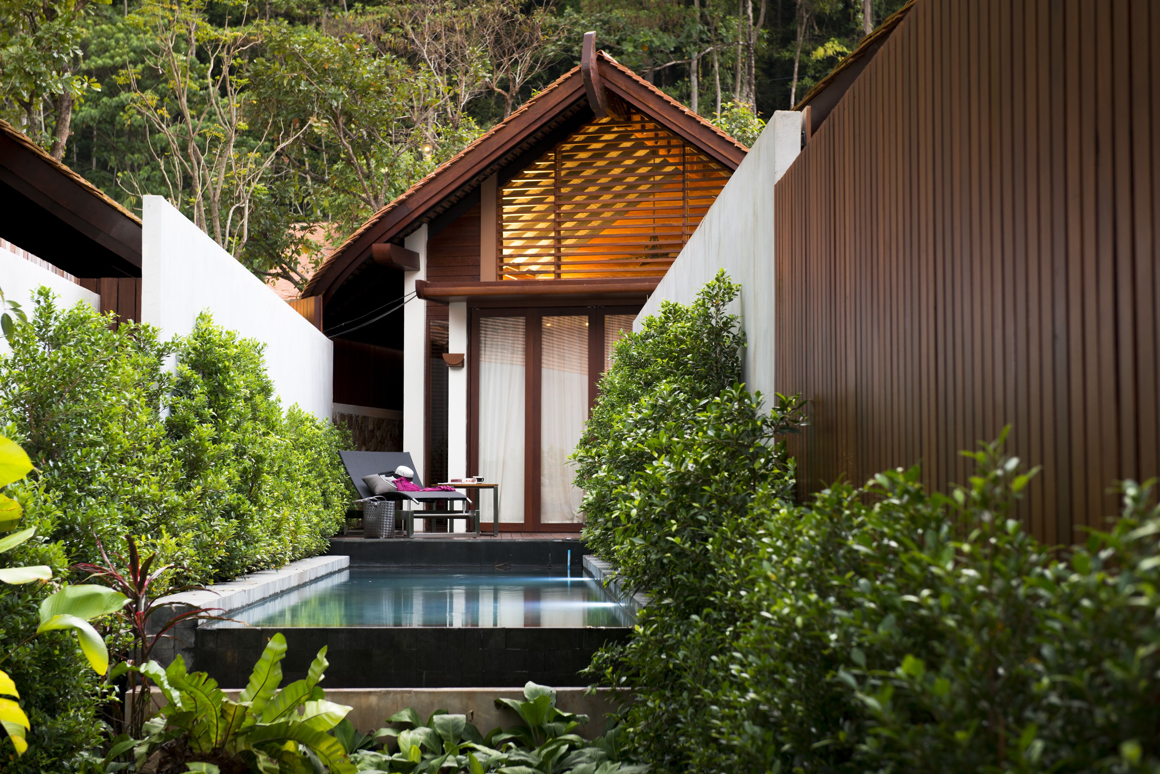 A pool area with a wooden deck, a lounge chair, and a small table.