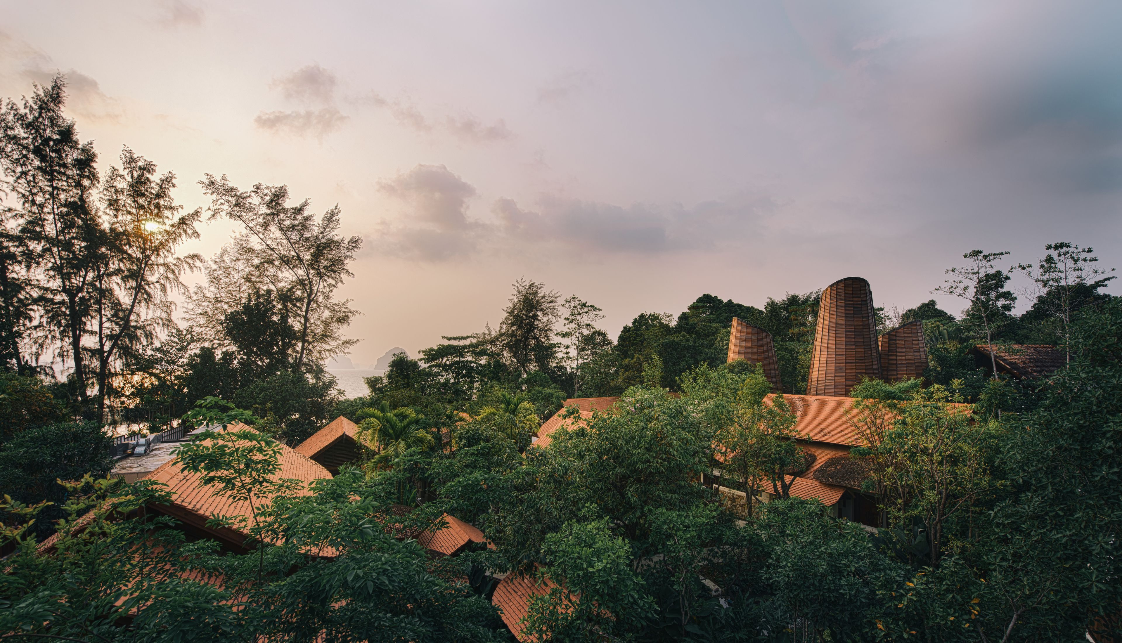 A tropical resort with traditional architecture, lush greenery, and a serene landscape.