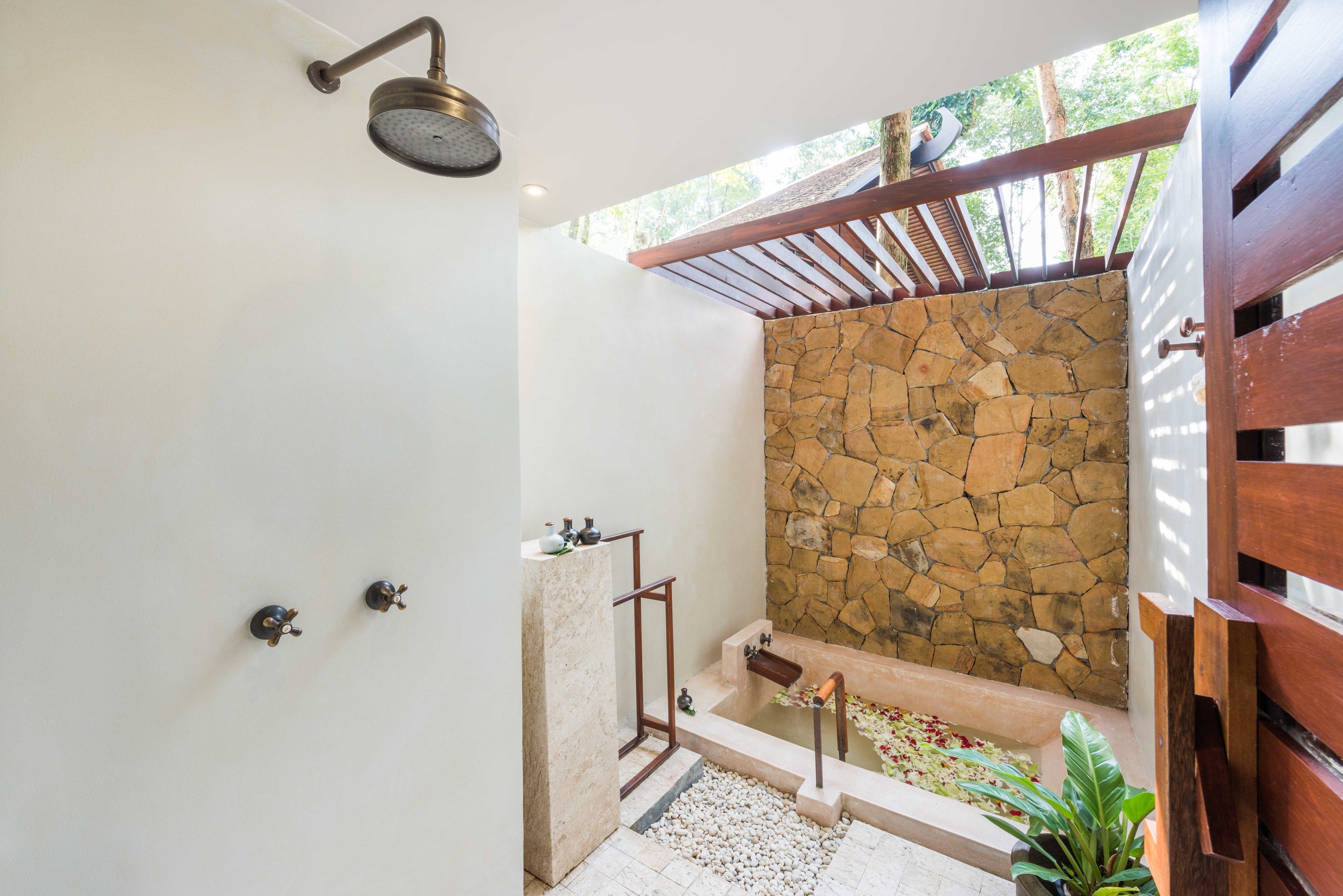 Ein modernes Badezimmer mit Steinwand, Dusche und einem kleinen Poolbereich.