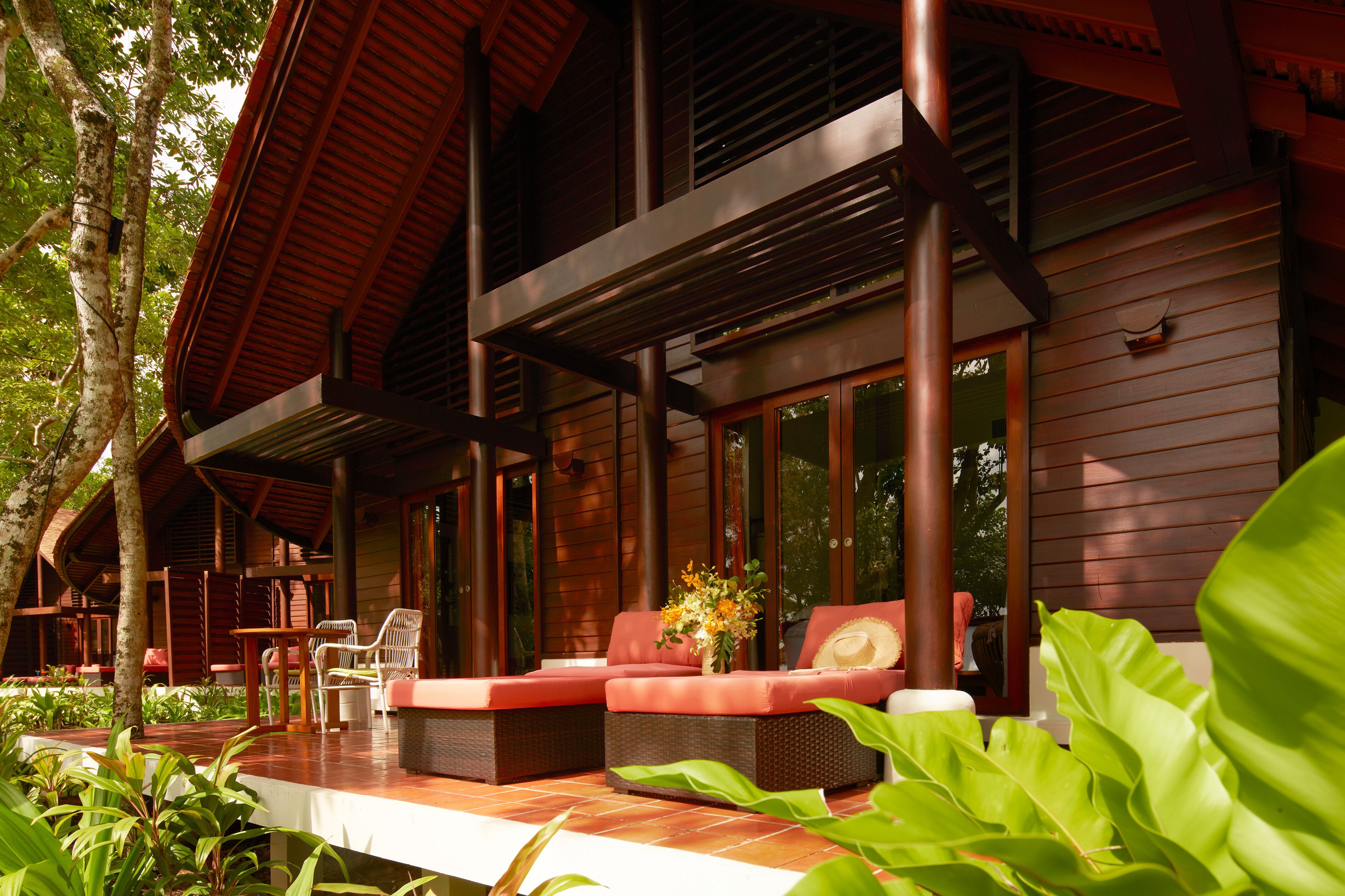 A wooden house with a covered porch, outdoor seating, and large windows.