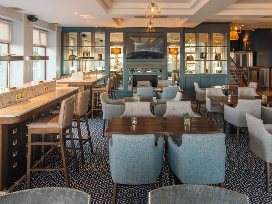 Un restaurant doté d’un bar, de plusieurs espaces pour s’asseoir et offrant une vue sur l’extérieur.