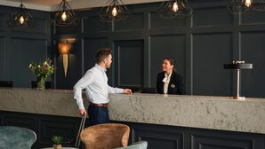 Un espace d’accueil doté d’un comptoir en marbre, de luminaires suspendus et de fauteuils rembourrés.