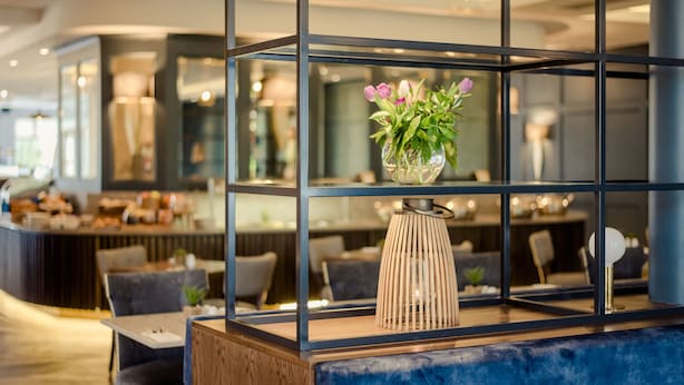 Un intérieur moderne avec un comptoir en marbre bleu, un vase en verre rempli de fleurs et un luminaire en fibres tressées.