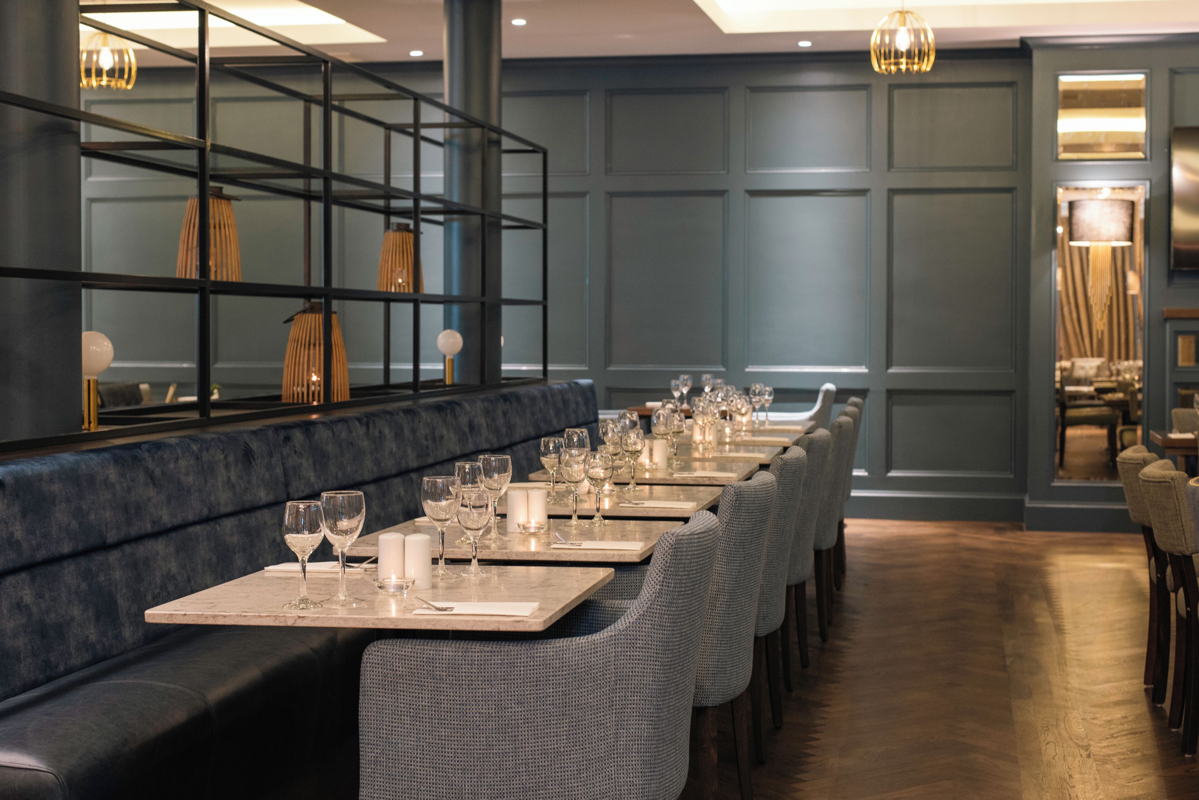 A restaurant with long tables, chairs, and a bar area with a mirror.