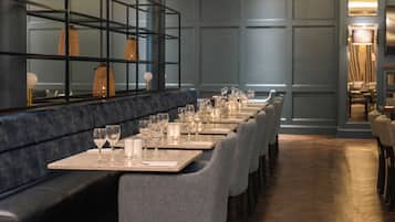 Ein Restaurant mit langen Tischen, Stühlen und einer Bar mit Spiegel.