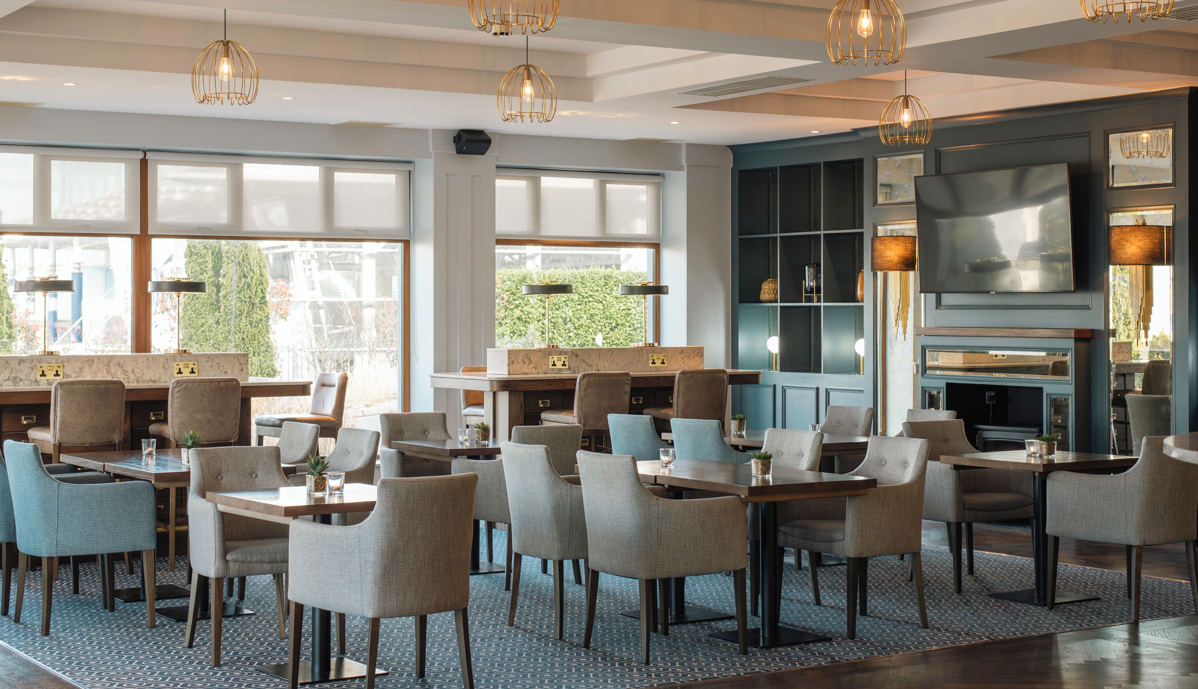 A modern hotel lobby with a seating area, large windows, and a fireplace.