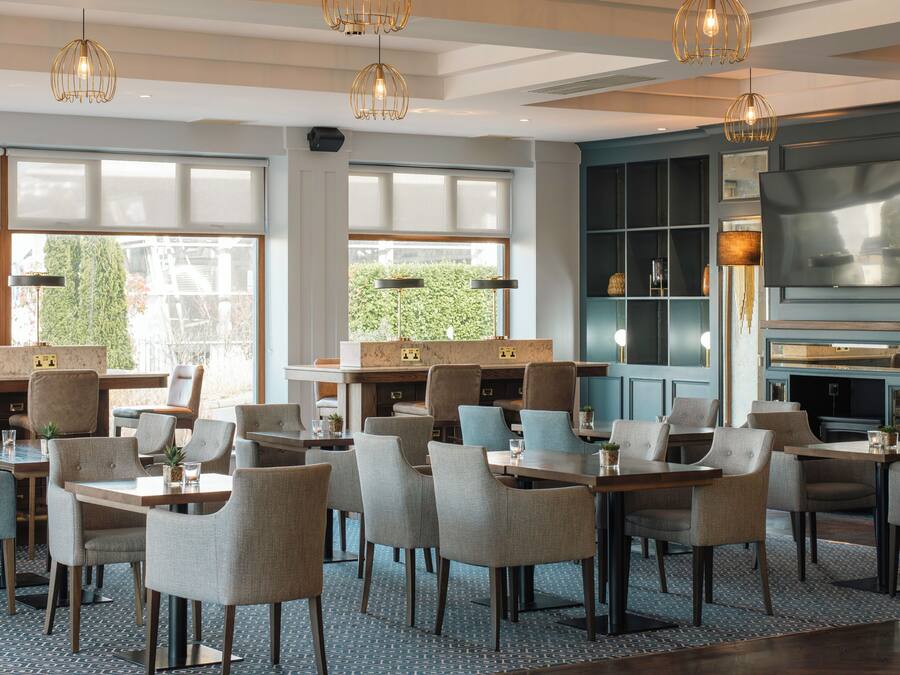 A modern hotel lobby with a seating area, large windows, and a fireplace.