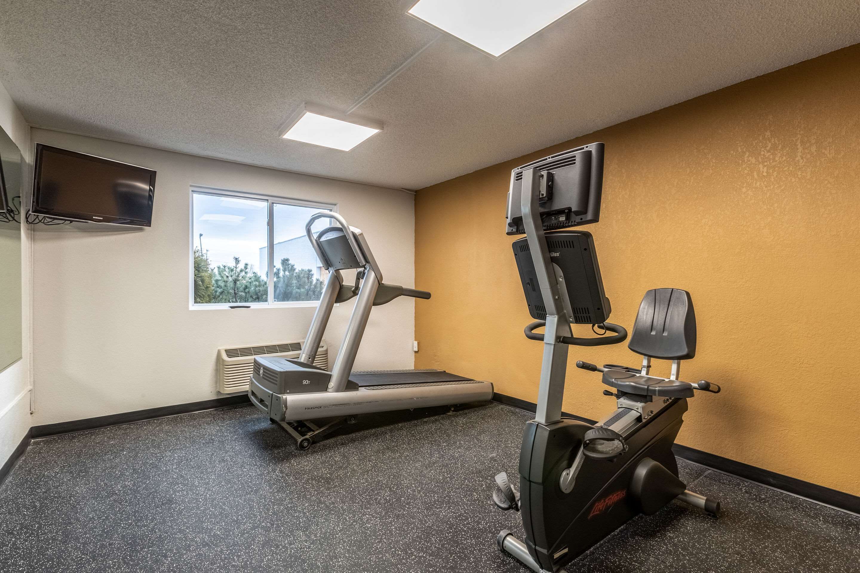 Un gimnasio con cinta de correr, elíptica y bicicleta estática.