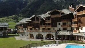 Um hotel com várias varandas, piscina e fachada de pedra.