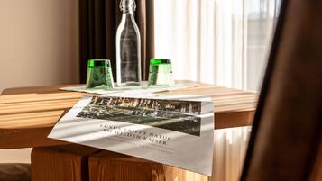Een houten tafel met een brochure, twee groene glazen flessen en een heldere fles met een rode dop.