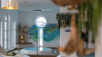 Une salle de spa dotée d’un grand miroir, d’une baignoire et d’une fresque murale.