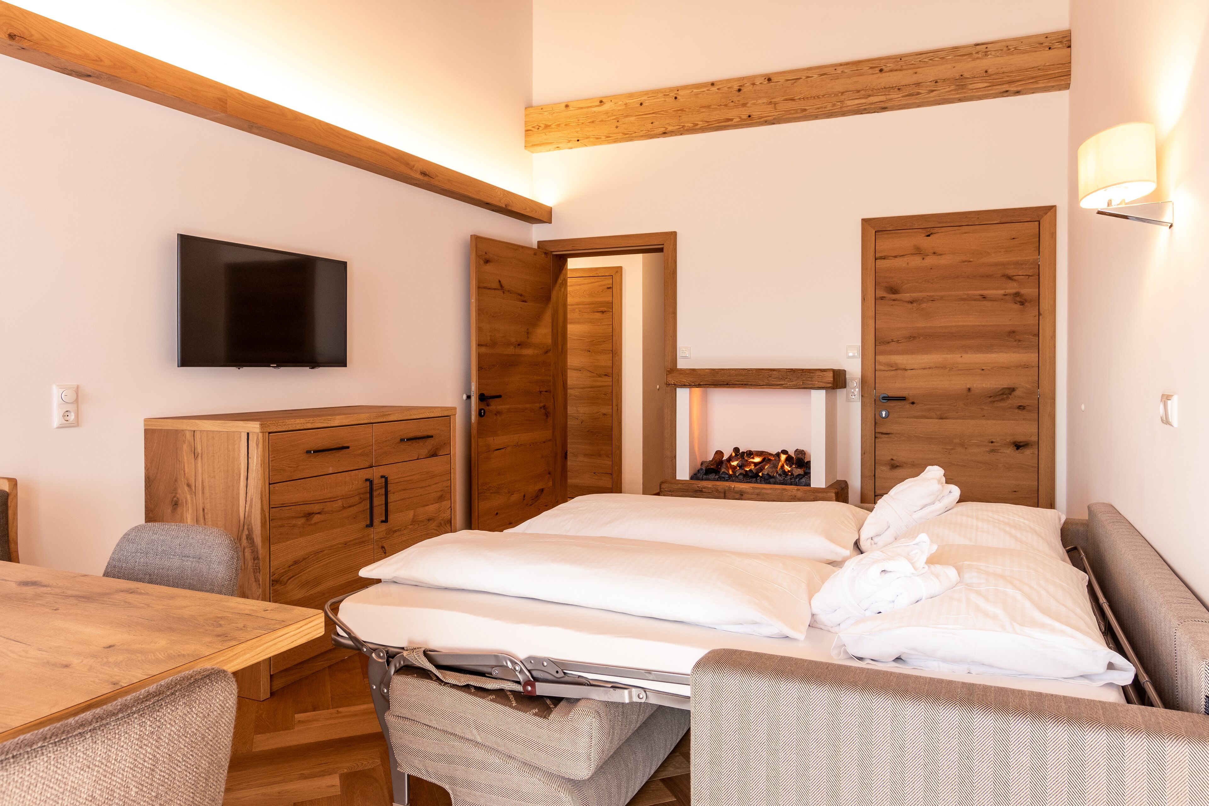 Une chambre à coucher avec un lit, une télévision, des meubles en bois et une cheminée.