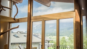 A spacious room with wooden floors, large windows, and a view of a mountainous landscape. - Hotel Hochfilzer (Ellmau)