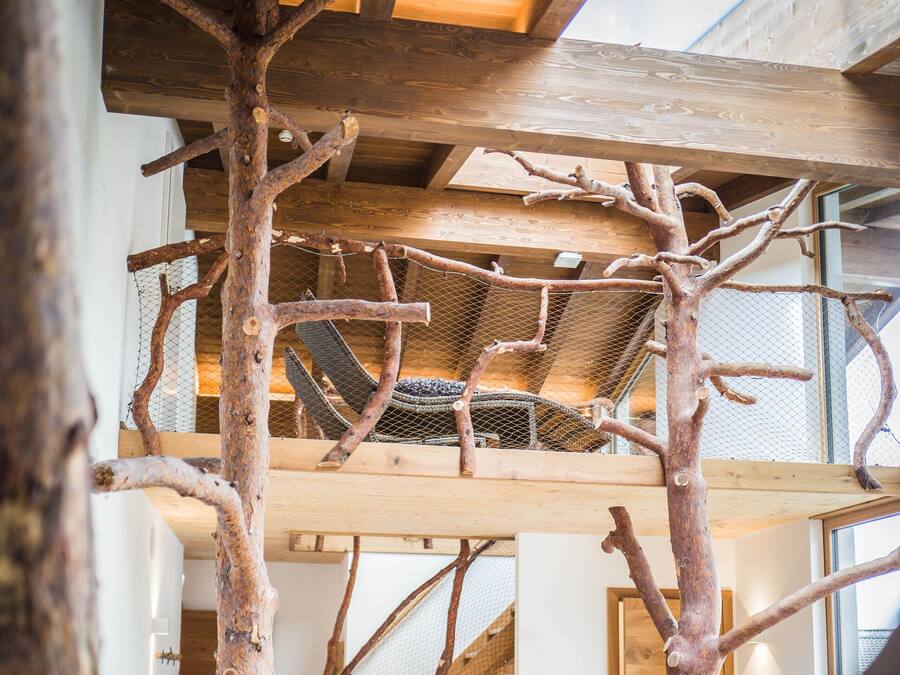 Ein Zimmer mit einer Holzkonstruktion, einer Hängematte und einer Treppe.