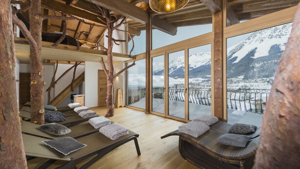A spa room with wooden beams, a wooden staircase, and a view of snow-covered mountains. - Hotel Hochfilzer (Ellmau)