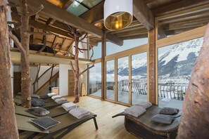 Un cuarto de spa con vigas de madera, una escalera de madera y vistas a montañas nevadas.