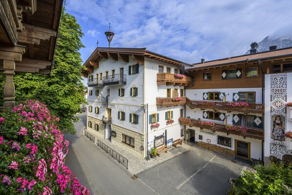 Un edificio tradicional europeo con varios balcones, fachadas de madera y jardineras con flores.