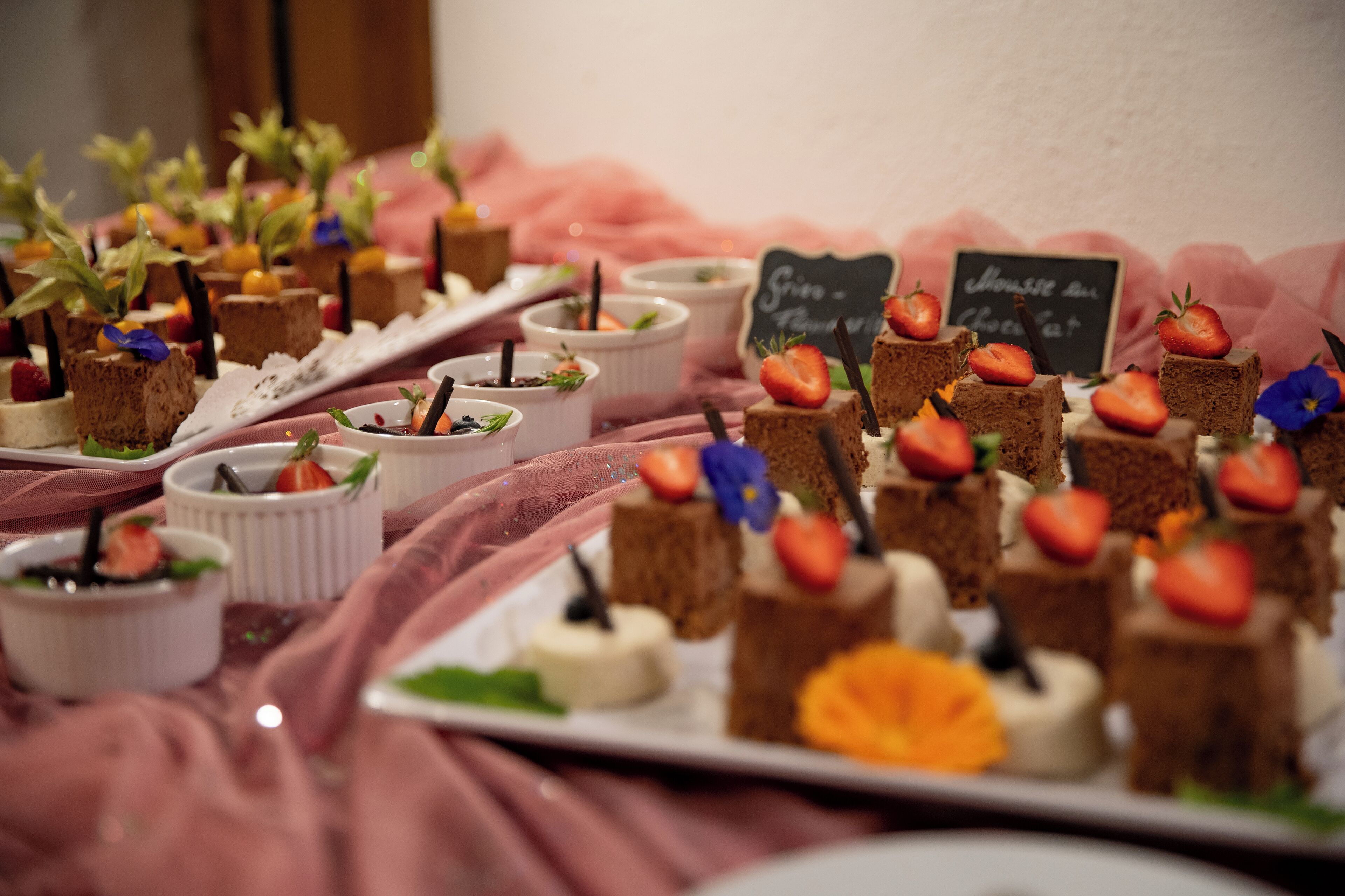 Une table où sont présentés divers desserts, ainsi qu’un panneau noir sur lequel est écrit un message.