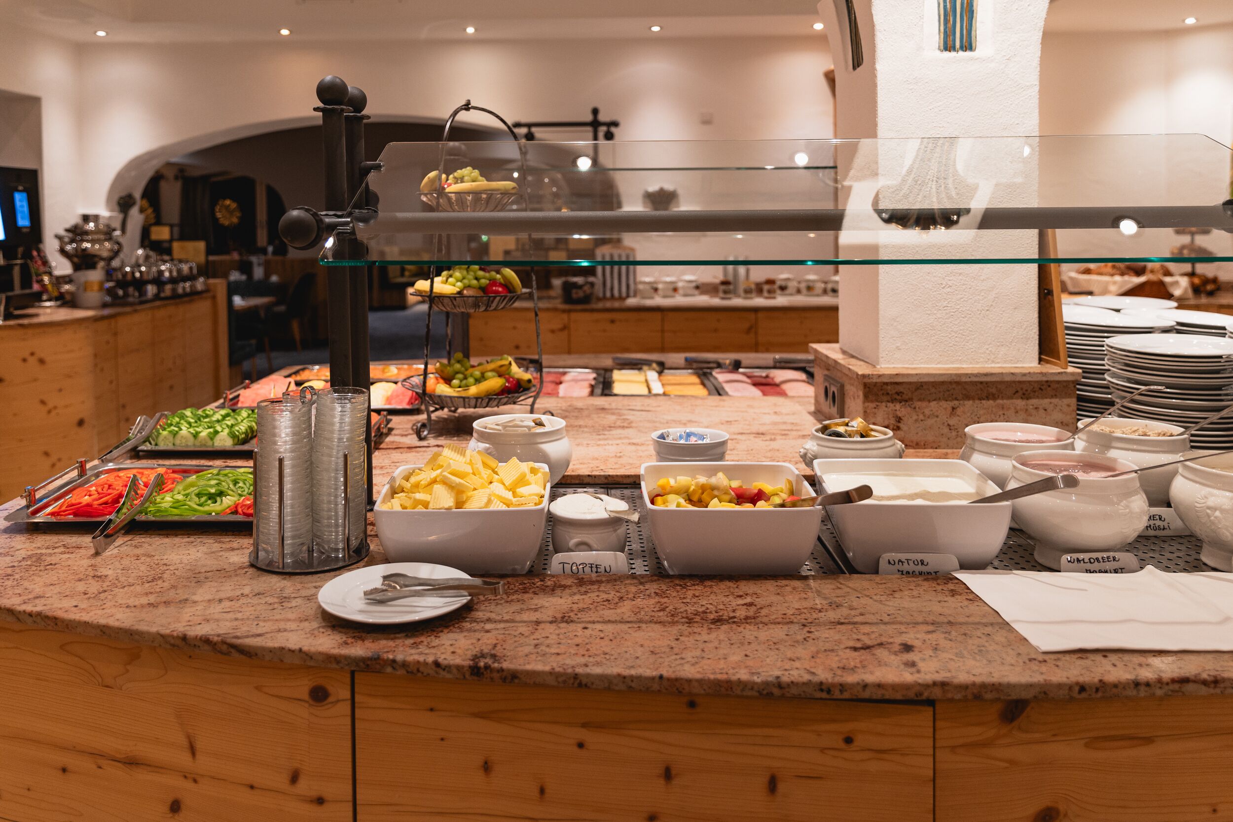 A buffet with various food items and utensils, including bowls of fruits, vegetables, and different types of spreads.