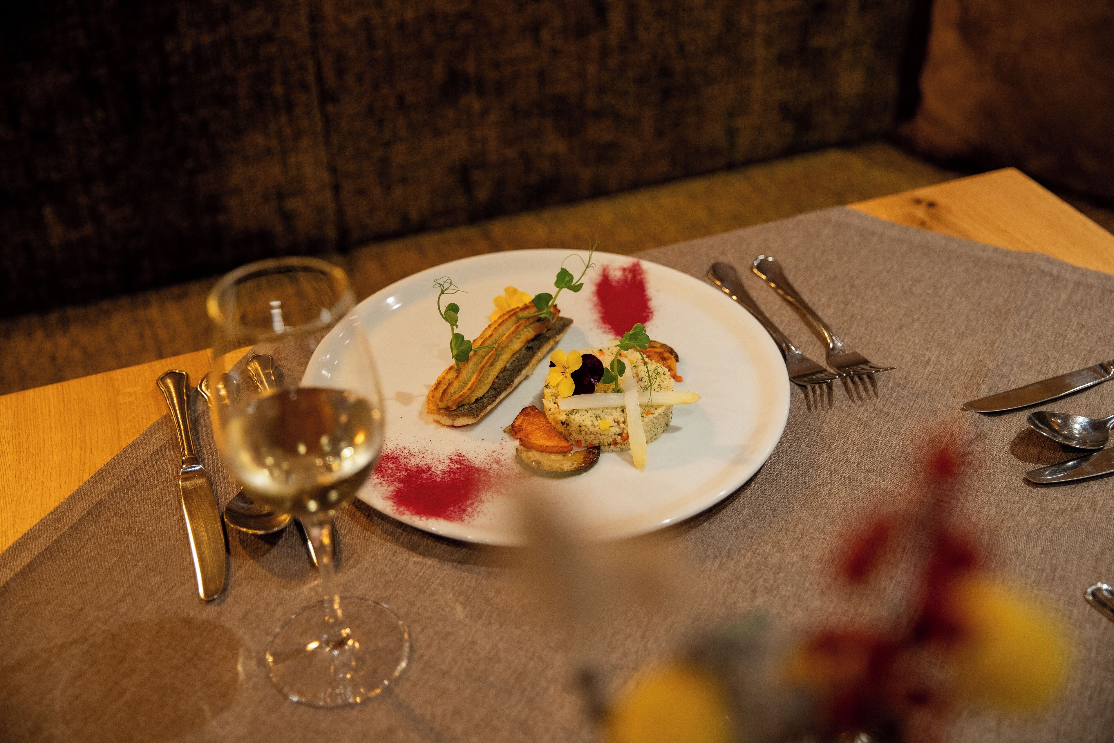 A dining table with a plate of food, a wine glass, and cutlery.