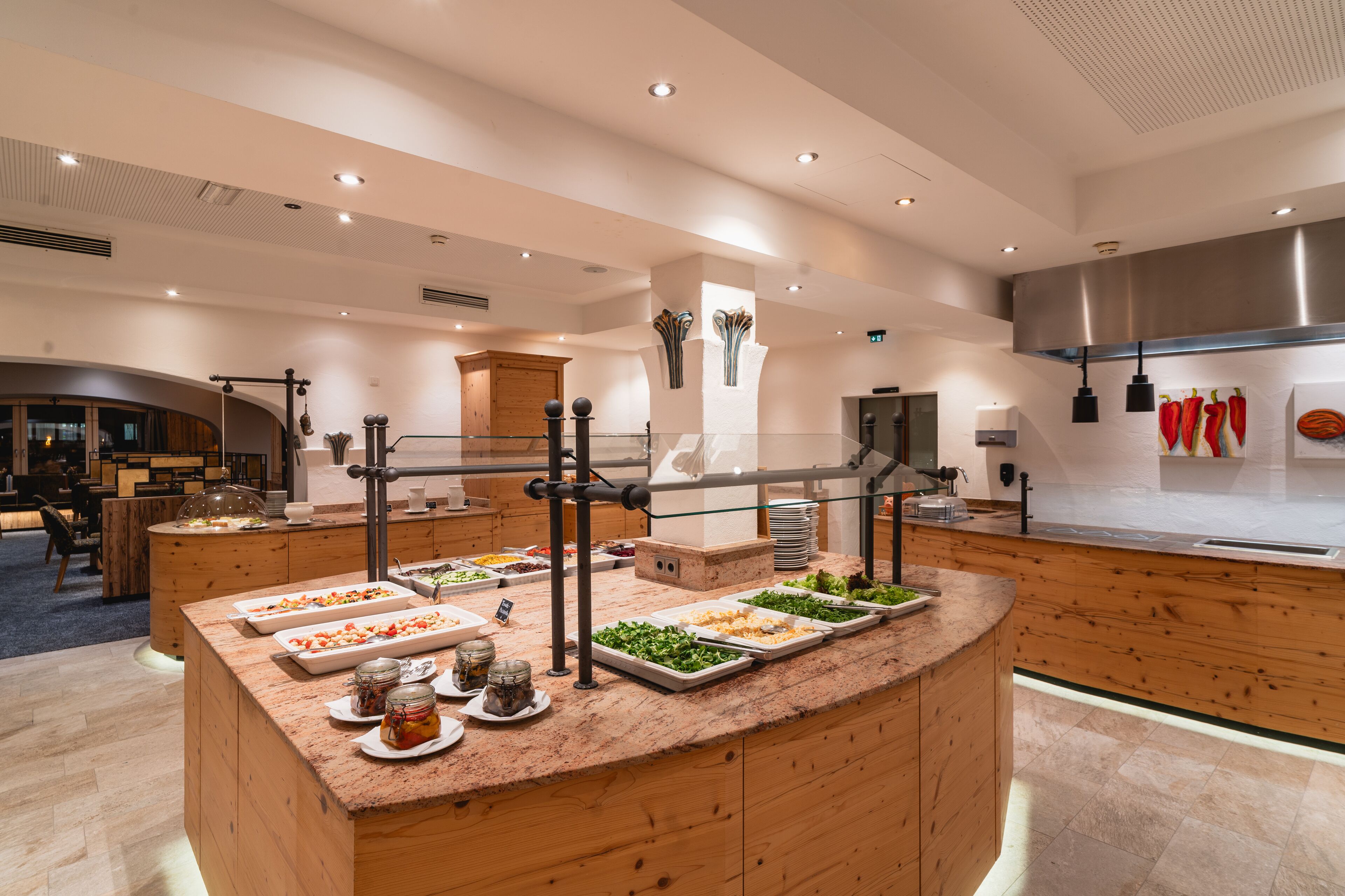 A buffet area with various food stations, wooden counters, and a modern kitchen in the background.