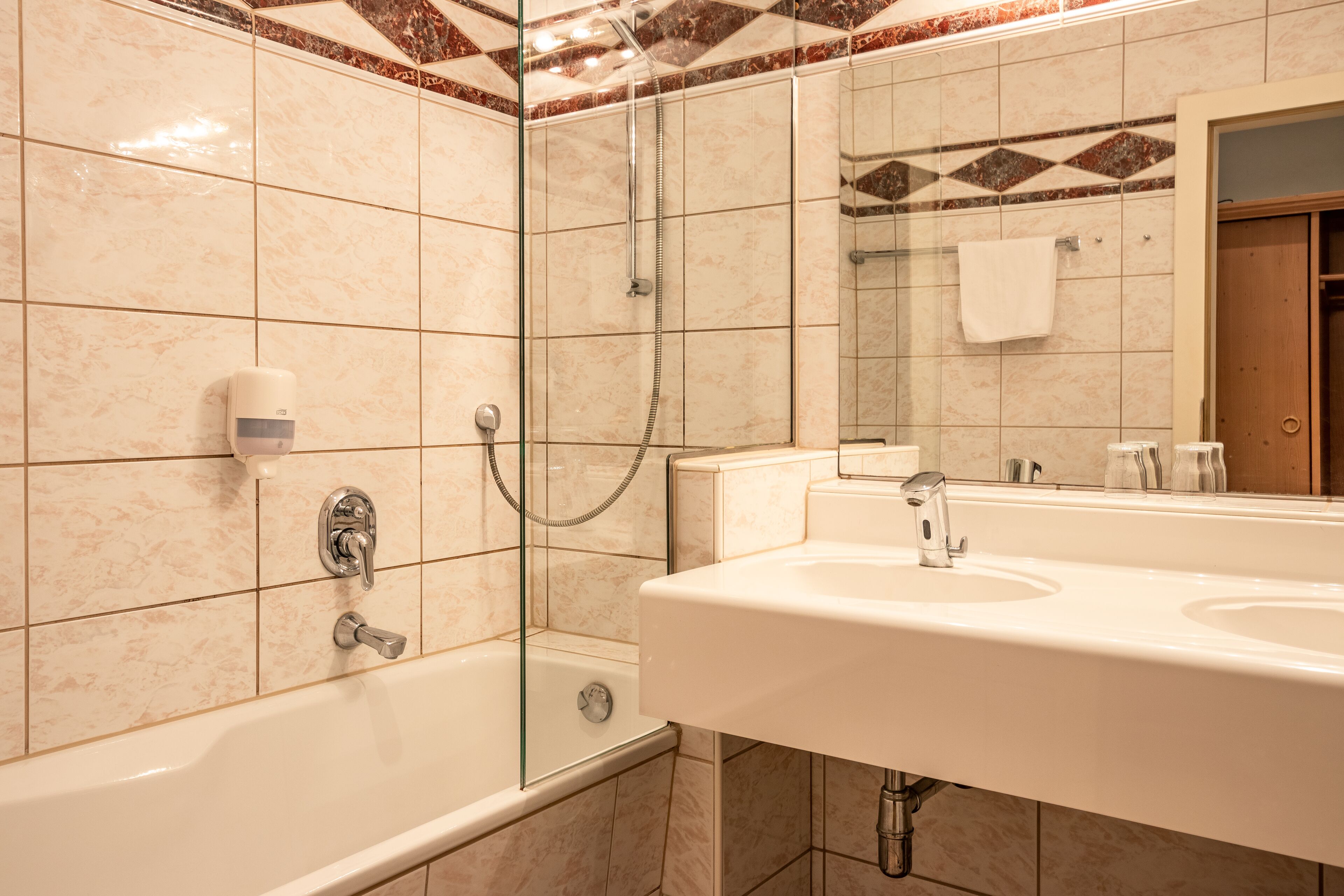 A bathroom with a glass-enclosed shower, a sink, and a mirror.