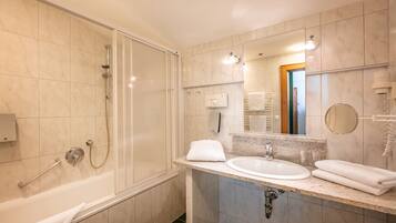 A modern bathroom with a glass-enclosed shower, a sink with a mirror, and a towel rack.