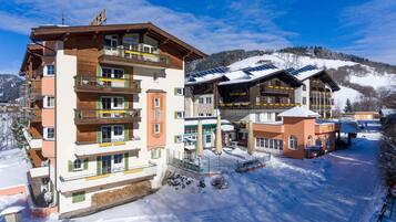 A multi-story hotel with balconies, a restaurant, and a ski resort in the background.