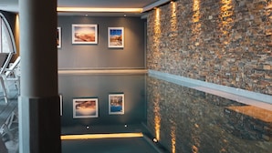 A hallway with a stone wall and framed pictures, a bench, and a pillar. - Le Val Thorens, a Beaumier Hotel (Les Belleville)