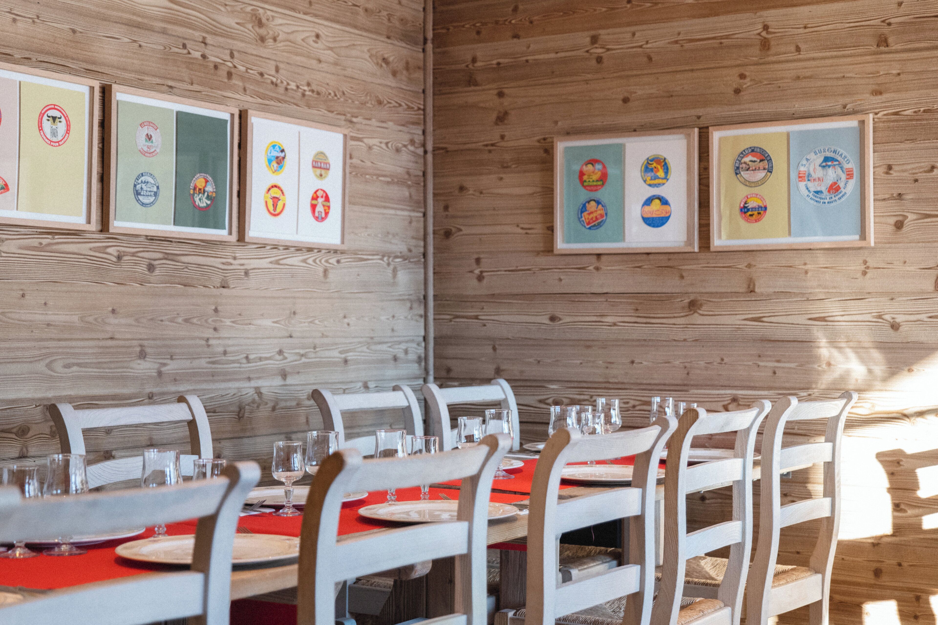 Ein Essbereich mit Holzwänden, gerahmten Zertifikaten an der Wand und einem Tisch mit weißen Stühlen und einer roten Tischdecke.
