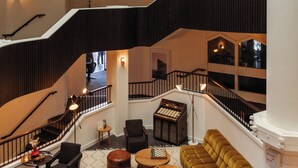 A multi-level interior with a central staircase, seating areas, and a piano. - Le Val Thorens, a Beaumier Hotel (Les Belleville)