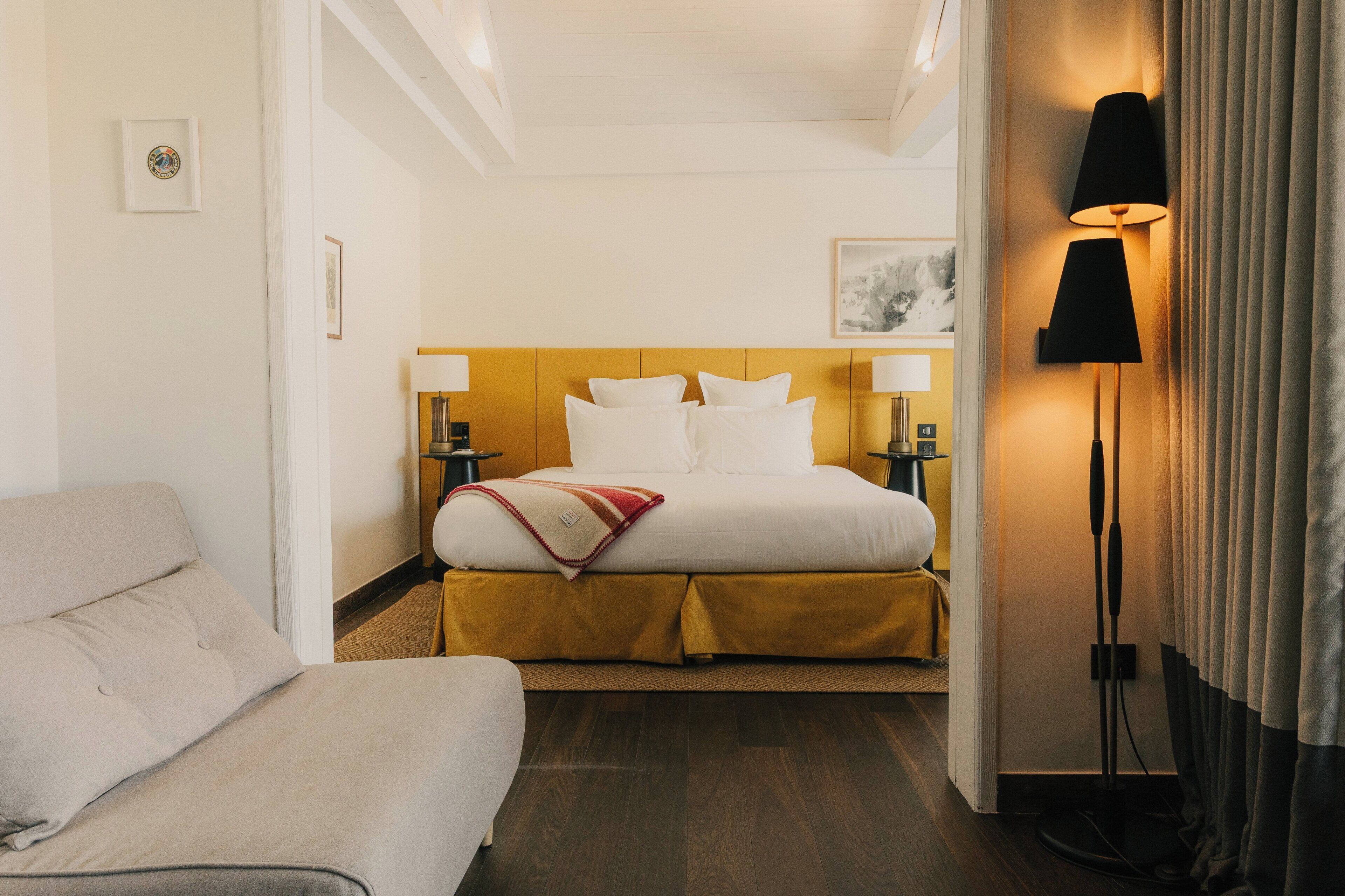 A hotel room with a bed, bedside tables, a lamp, and a couch.