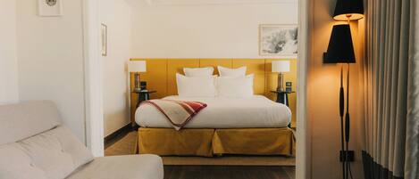 A hotel room with a bed, bedside tables, a lamp, and a couch.