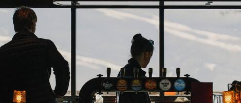 A bar with a bartender and a customer. There are bottles and a beer tap behind the bartender.
